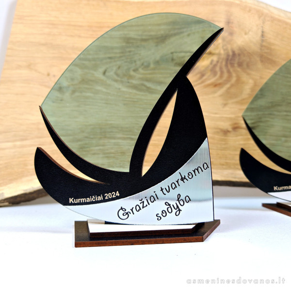 Apdovanojimas, burlaivis. Su graviruotu tekstu ant aukso arba sidabro spalvos plokštelės. Apdovanojimas byrės formos.